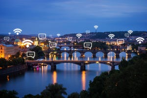 Lit buildings and bridges with connectivity icons in Prague, Czech Republic, at dusk.