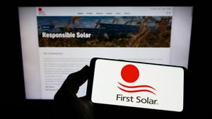 Person holding smartphone with logo of US renewable energy company First Solar Inc. on screen in front of website. Focus on phone display.