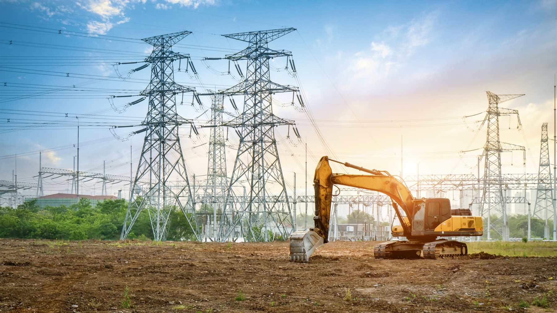 Excavator on the construction site with electric piles and substation in the distance