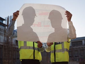 two men hold blueprints at data center construction site