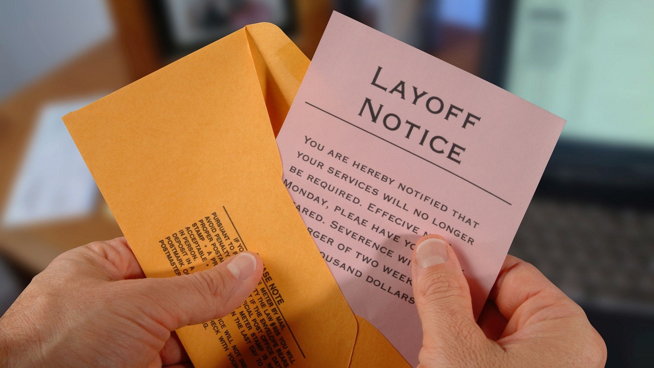 employee opening an envelope containing a layoff notice employee opening an envelope containing a layoff notice