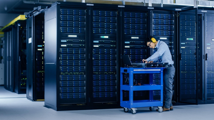In Data Center: IT Engineer Wearing Protective Muffs Installs New Hardware for Server Rack.