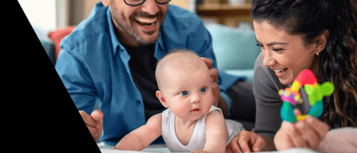 Smiling Family with Baby on White Surface and Colorful Toy