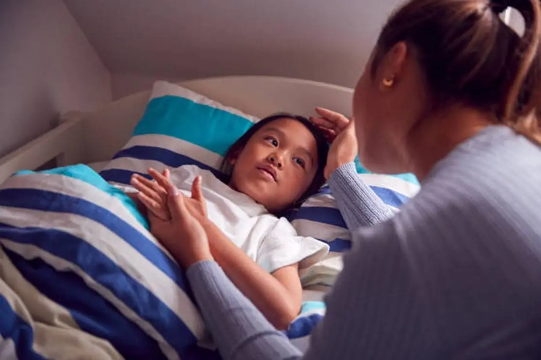 A Mother Comforting Her Child Who Is Lying in Bed 