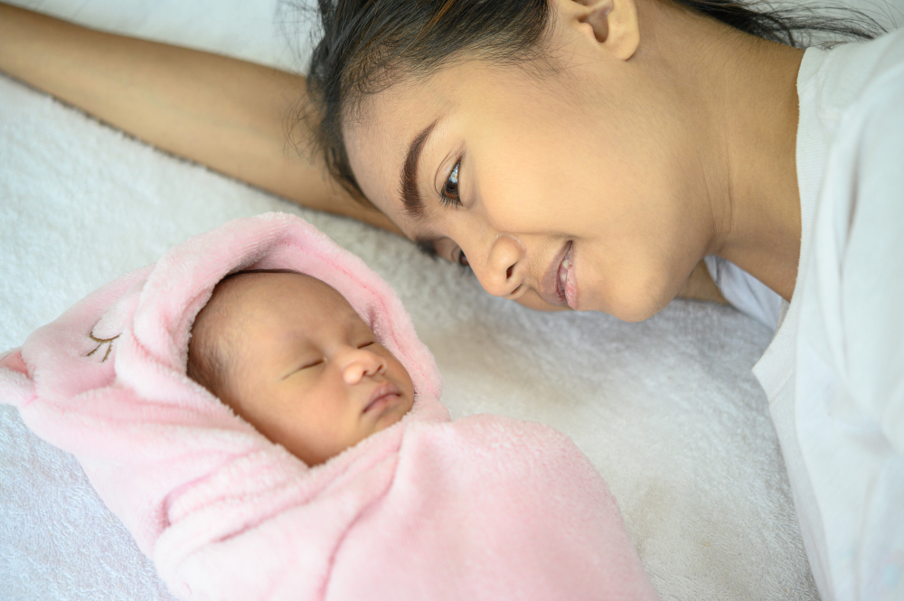 Mother lying on bed with newborn baby