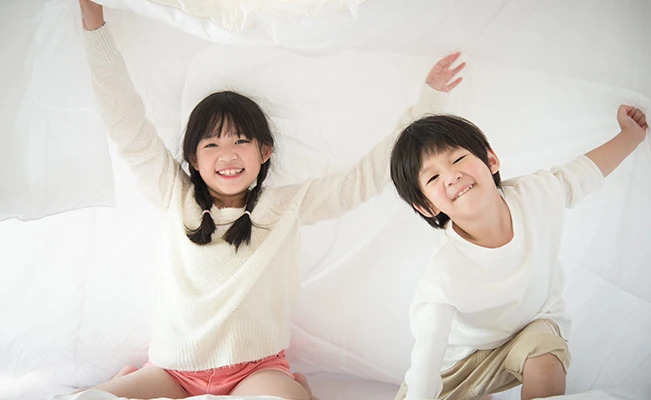 Siblings playing on bed 