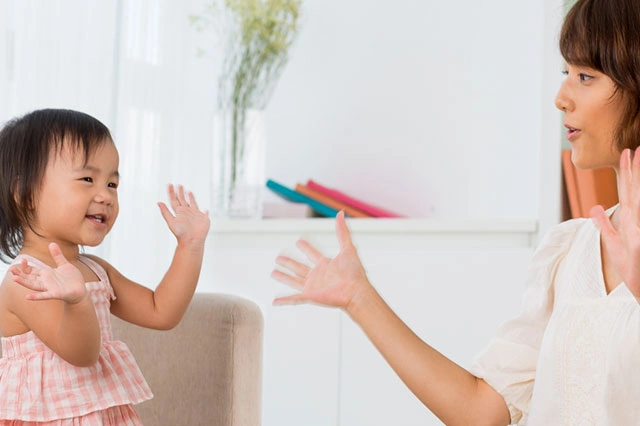 Mother And Her Child Raising Hands In A Playful Gesture In A Bright Room 