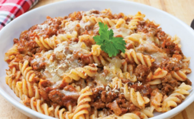 Meat pasta served on plate on wooden surface