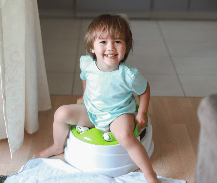 Niño sentado sonriente en su orinal, representando el buen funcionamiento del sistema digestivo y evacuaciones saludables.