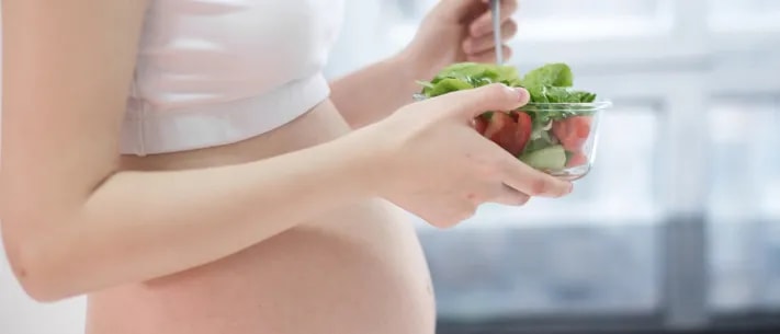 Close-up of pregnant woman eating salad