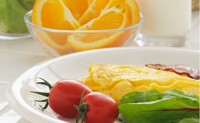 Fruits on different plates and bowls with a glass of milk on the side