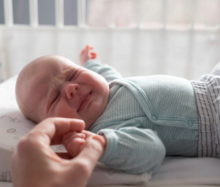 Bebé recostado llorando con expresión de molestia, acompañado de texto sobre el reflujo en bebés, sus causas y cómo aliviarlo.