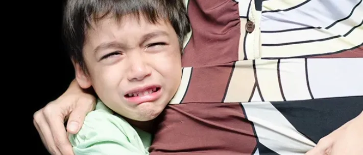 Young child with upset stomach clinging to parent for comfort