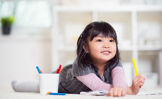Young girl on the floor and holding a yellow pen
