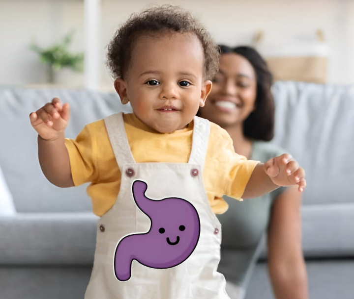Bebé sonriente caminando con ilustración de estómago feliz en su ropa, representando consejos para aliviar cólicos.