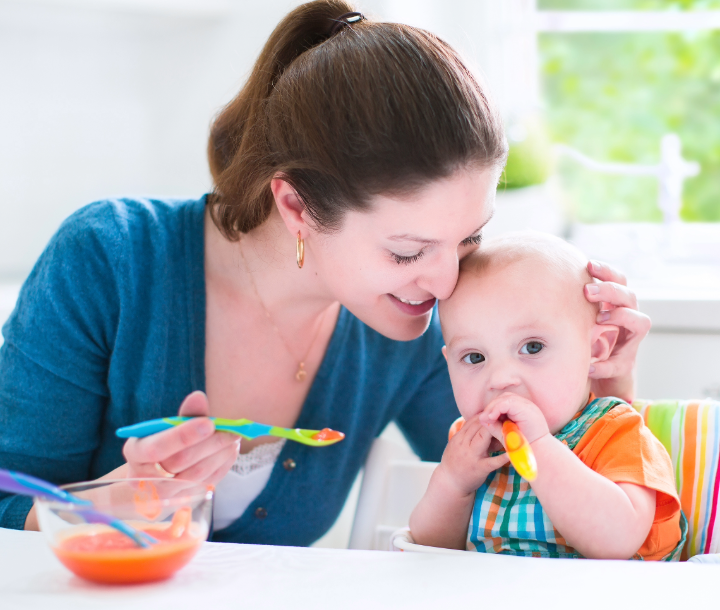 Bebé de seis meses siendo alimentado con cuchara, acompañado de texto sobre la introducción de alimentos sólidos en su dieta.