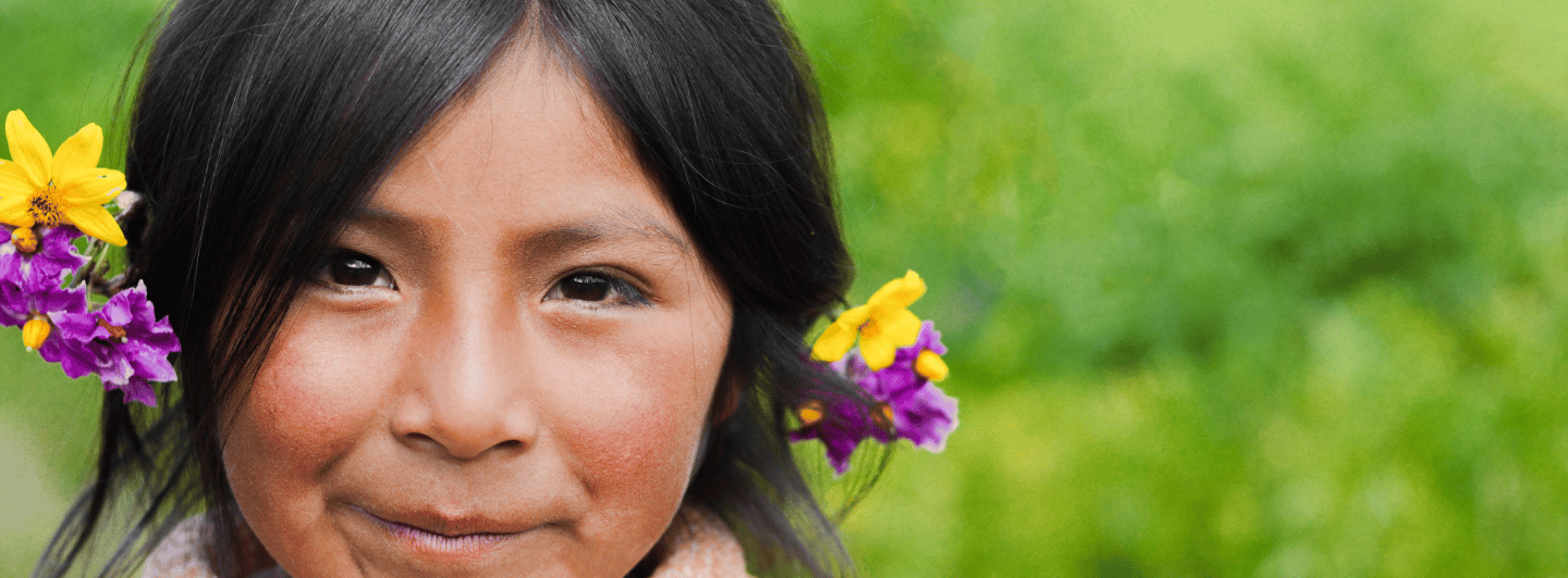 Niña peruana sonriendo con una flor en el cabello, simbolizando la lucha contra la anemia infantil y la importancia del hierro para un futuro saludable.