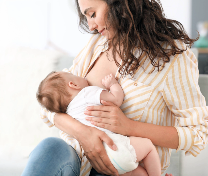 Madre amamantando a su bebé en casa, representando los beneficios y consejos prácticos de la lactancia materna.
