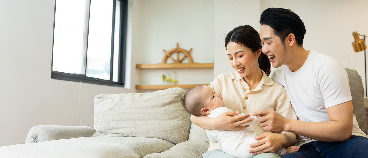 Mother Carrying Baby Beside Father, Both Smiling Happily While Looking At Their Baby