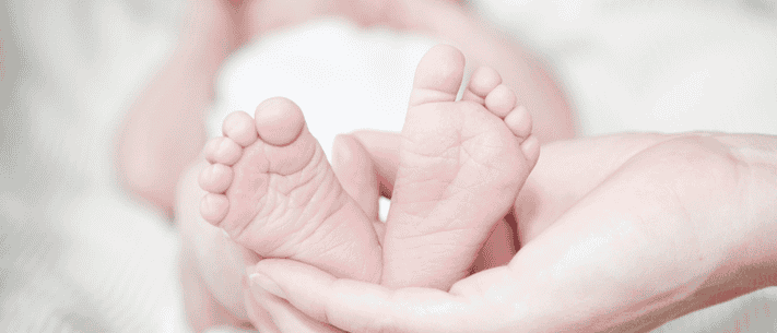 Close-Up of a Newborn Baby’s Feet Cradled in an Adult’s Hands