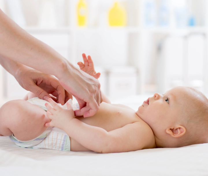 Bebé acostado con pañal blanco, acompañado de texto sobre cómo detectar posibles signos de enfermedad en el pañal del bebé.