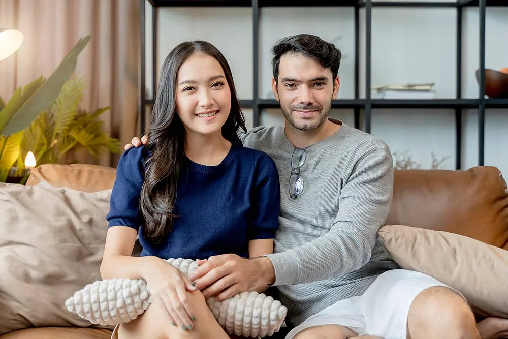 Smiling couple sitting together on living room couch