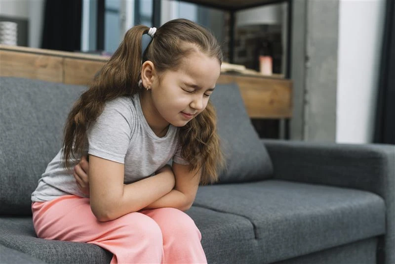 Young girl clutching stomach in digestive pain.