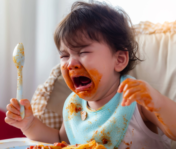 Bebé con diadema de flores siendo alimentado con cuchara, junto a texto sobre la importancia del DHA como ácido graso esencial para el desarrollo del cerebro infantil.