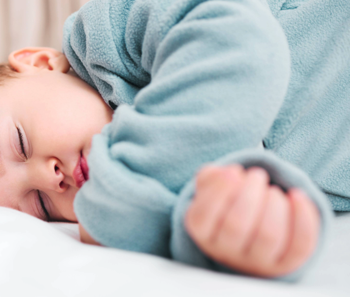 Bebé dormido plácidamente después de alimentarse, mostrando la relación entre nutrición y sueño saludable.