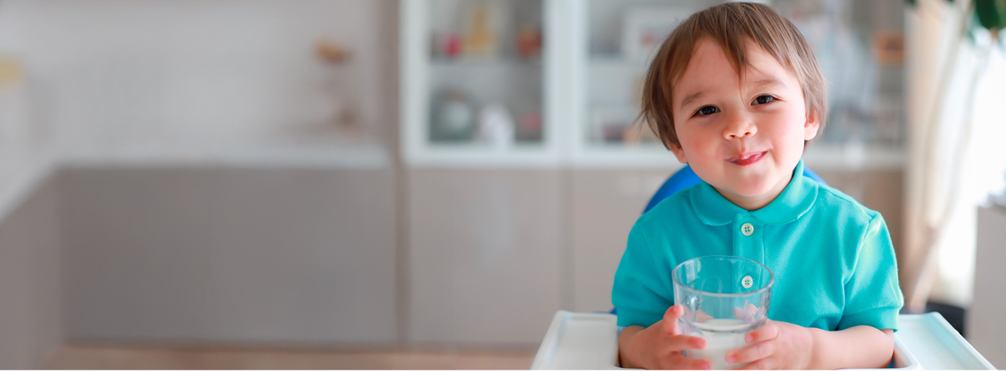 Niño sentado en el comedor disfrutando un vaso de leche