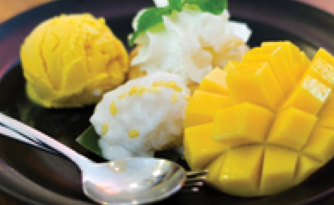 Tropical avocado mango split dish served on black platter with spoon
