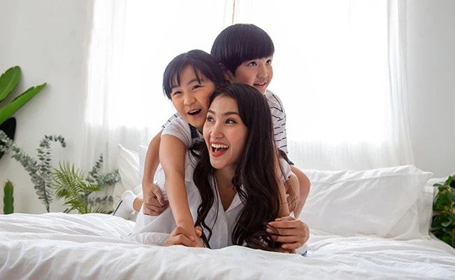 Mother and two children playing on a bed