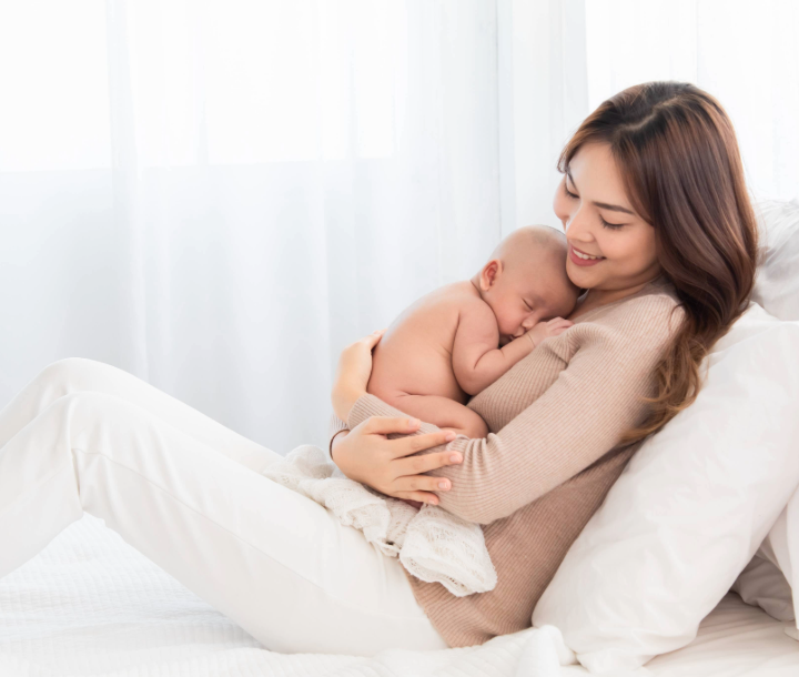 Madre abrazando a su bebé mientras lo amamanta, beneficios de la leche materna.