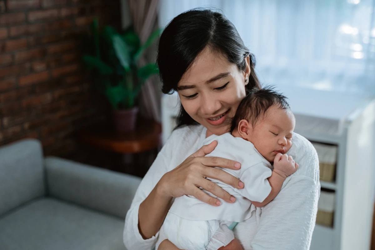 Mother cradling baby close to her chest.