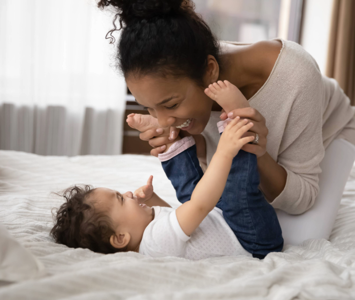 Padre sosteniendo a su bebé mientras juega con sus piernas, acompañado de texto sobre la comunicación del bebé y el inicio del desarrollo del lenguaje.