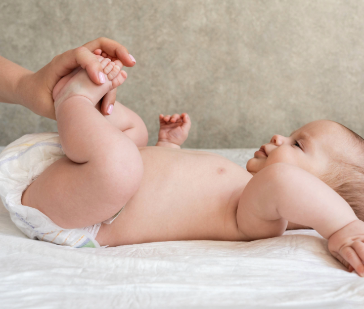 Bebé de seis meses recostado en su cuna mientras un adulto lo acaricia, acompañado de texto sobre los logros y avances en esta etapa de crecimiento.