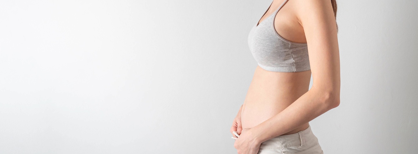 Mujer en las primeras semanas de embarazo tocando su vientre, símbolo de nutrición y cuidado prenatal desde el inicio.