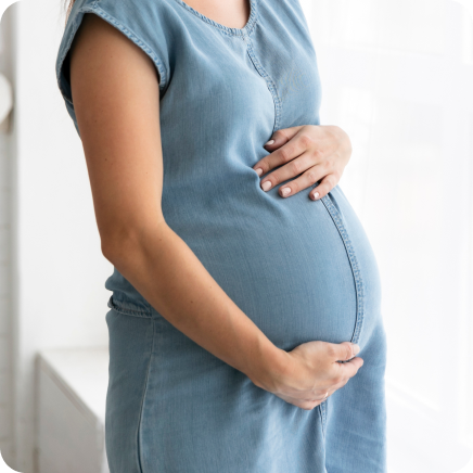 Close-Up Of Pregnant Woman's Belly In Blue Shirt, Holding Her Belly