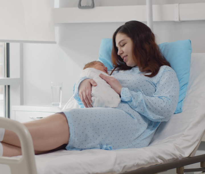 Mujer descansando con su bebé recién nacido en brazos, recibiendo apoyo y consejos tras el parto