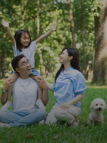 Family With Daughter And Dog Sitting In A Park