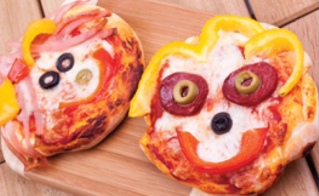 Two smiley pizzas on wooden board