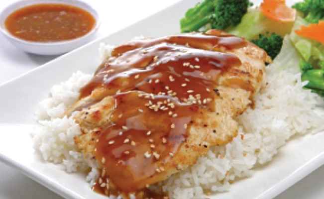 Chicken teriyaki served with rice and vegetables on white platter, dipping sauce on the side