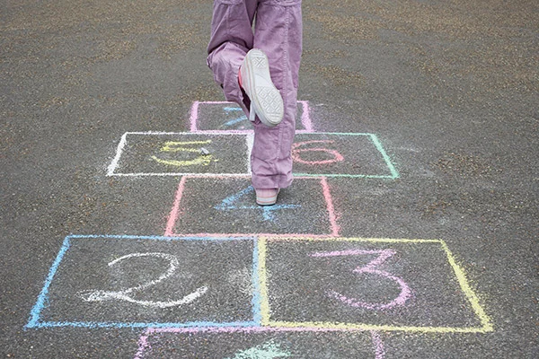 Close-up of child playing hopscotch.