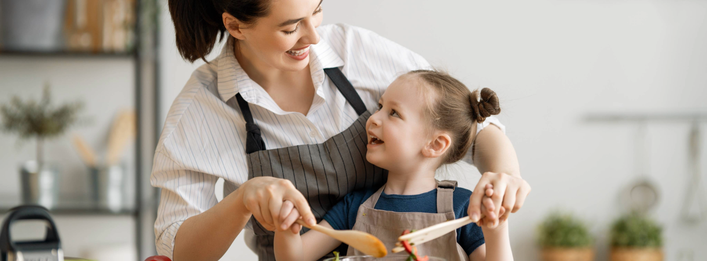 Maujer madre de una niña cocinando juntas. Alimentación para las mamás.