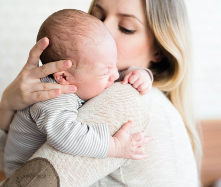 Madre cargando a su bebé en brazos, acompañado de texto sobre la diarrea en bebés y cómo reconocer sus causas y soluciones.