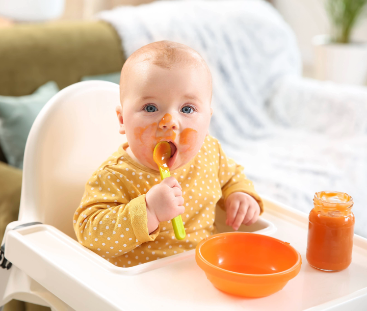 Bebé comiendo con cuchara, acompañado de texto sobre el aparato digestivo infantil y los problemas digestivos comunes durante la lactancia y los primeros años de vida.