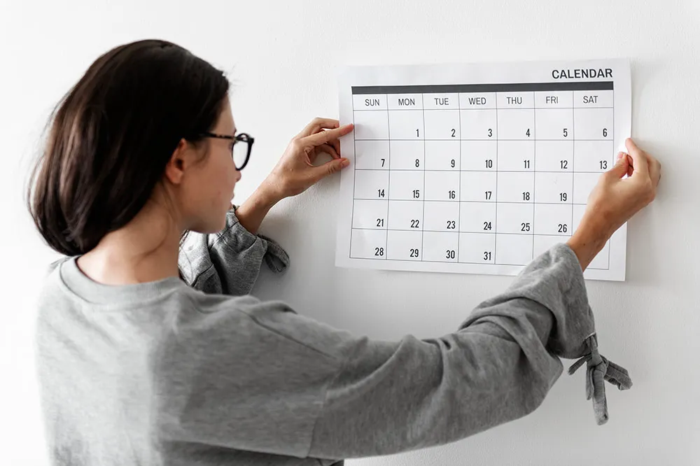 Woman hanging wall calendar to track important dates