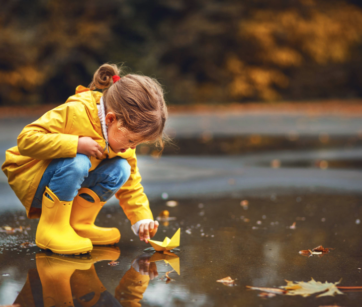 Niño jugando en charcos con botas de lluvia, simbolizando la importancia de un sistema inmune fuerte para prevenir infecciones.