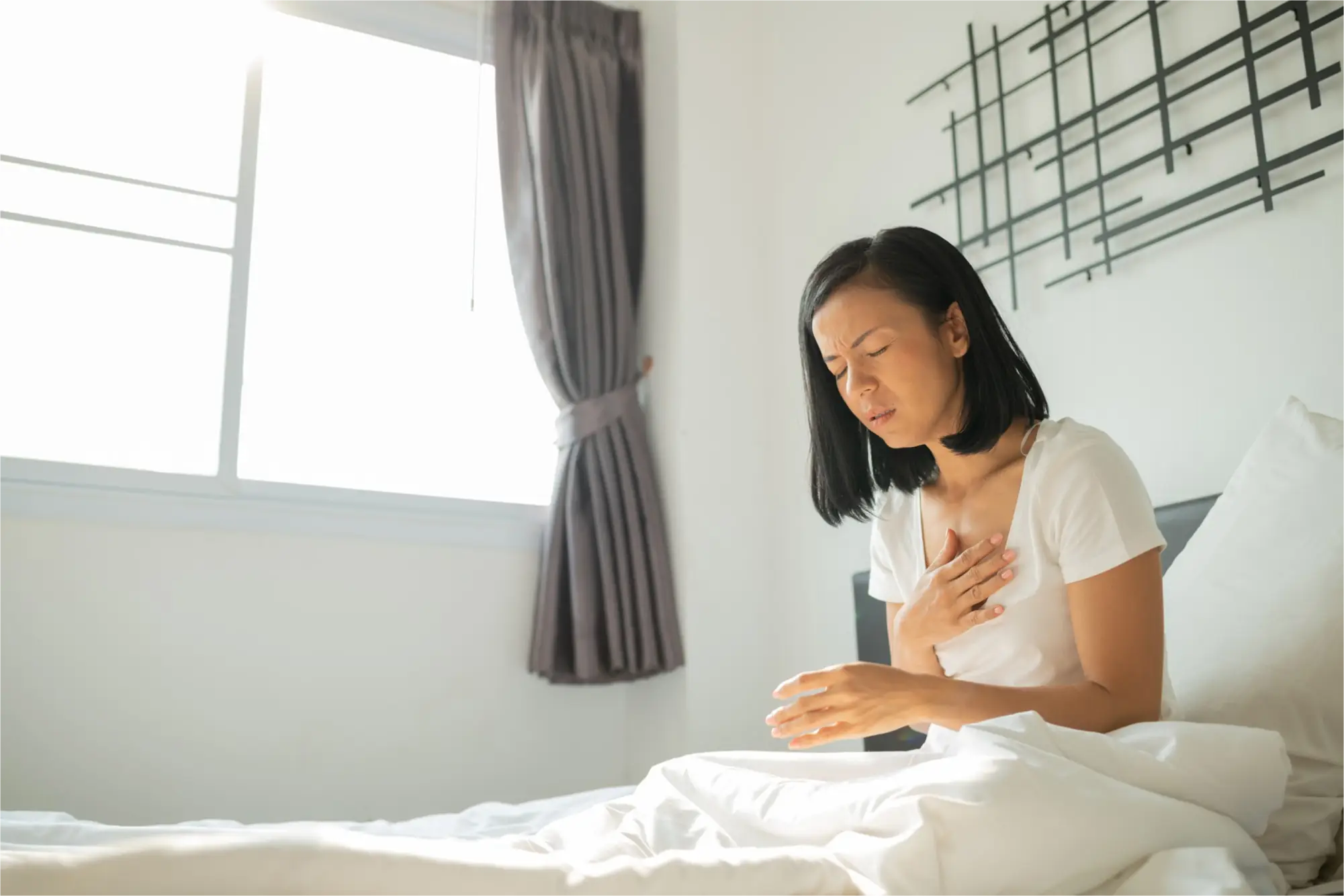 Woman in bed feeling nauseous or experiencing heartburn.