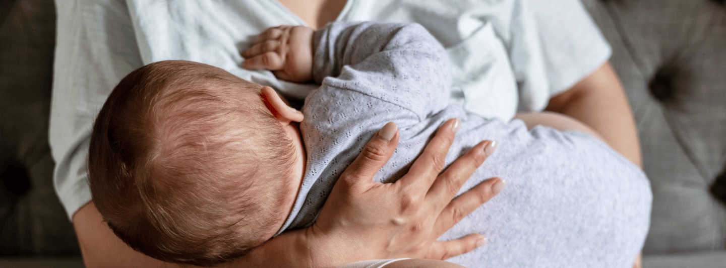 Madre amamantando a su bebé en casa, reflejando los beneficios de la lactancia materna para la nutrición y el desarrollo infantil.